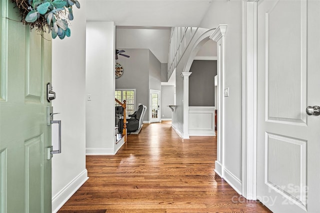 foyer entrance with ceiling fan, baseboards, wood finished floors, ornate columns, and stairway