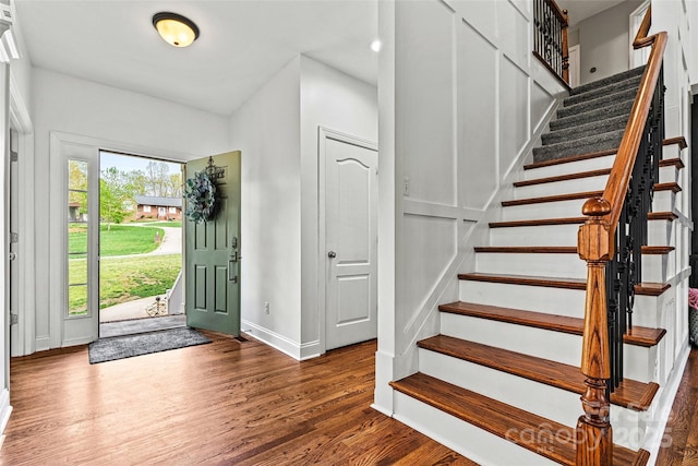 entrance foyer with baseboards, wood finished floors, and stairway