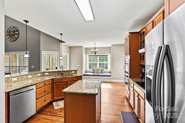 kitchen featuring a sink, dark wood-style flooring, appliances with stainless steel finishes, and brown cabinets