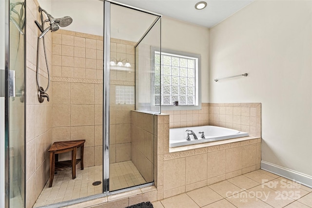bathroom featuring tile patterned floors, baseboards, a shower stall, and a garden tub