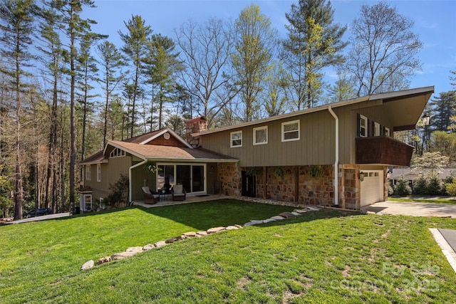 4075 Little River Rd, Hendersonville, NC 28739 - back of house featuring stone siding, concrete driveway, an attached garage, and a yard