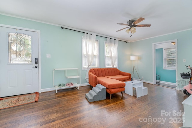 living area featuring crown molding, baseboards, a ceiling fan, and wood finished floors