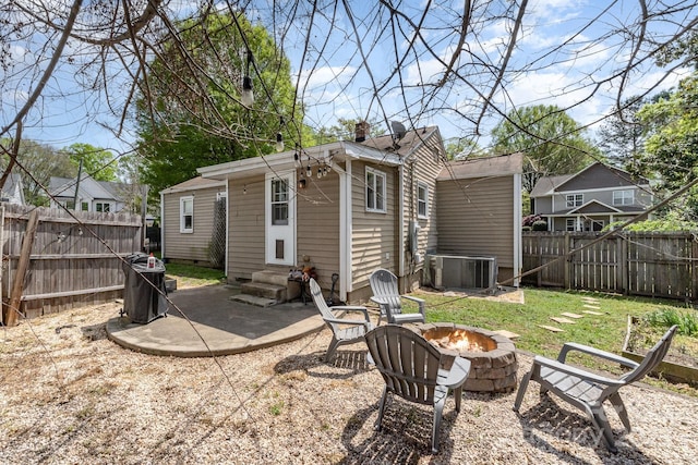 back of property with a fire pit, entry steps, a fenced backyard, cooling unit, and a patio