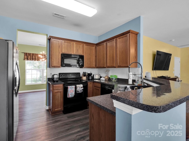 5102 Candleglow Ct, Indian Trail, NC 28079 - kitchen with a peninsula, dark countertops, dark wood-style floors, a sink, and black appliances