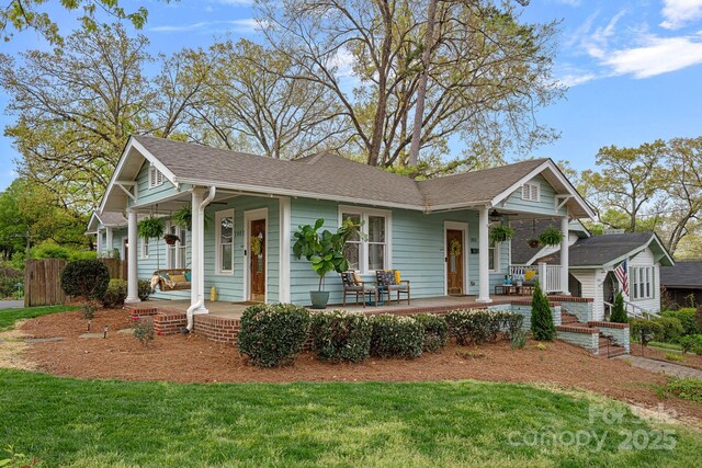 view of front of home featuring a porch, a shingled roof, and a front yard