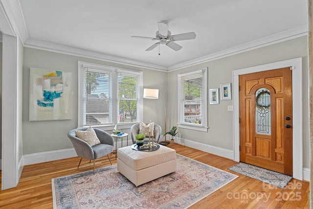 sitting room with a ceiling fan, baseboards, and crown molding