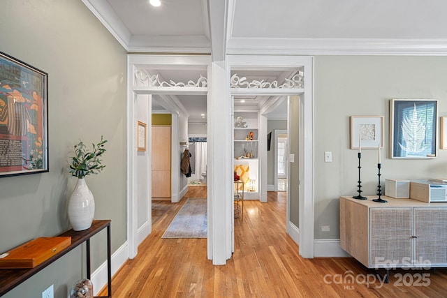 hallway featuring baseboards, light wood-style floors, and ornamental molding