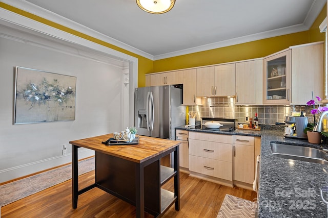 kitchen featuring stainless steel fridge with ice dispenser, light brown cabinets, a sink, crown molding, and decorative backsplash