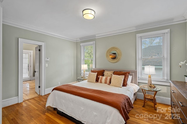 bedroom featuring baseboards, ornamental molding, and light wood-style floors
