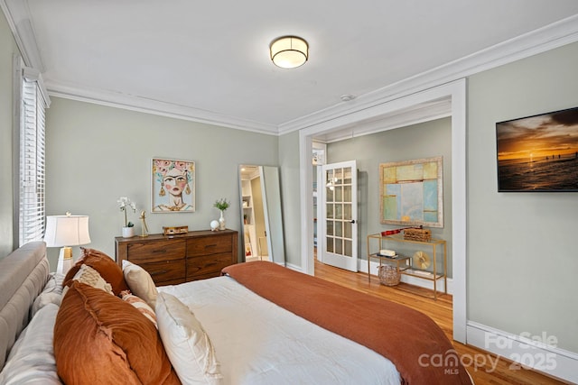 bedroom with baseboards, wood finished floors, and crown molding