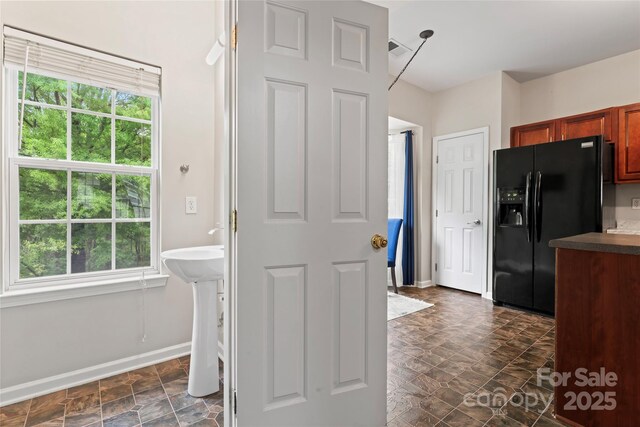 12905 Bullock Greenway Blvd, Charlotte, NC 28277 - kitchen featuring visible vents, black fridge, dark countertops, brown cabinets, and baseboards