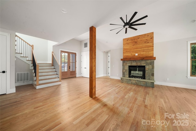 29 Wild Deer Trl, Zirconia, NC 28790 - unfurnished living room with stairway, light wood finished floors, french doors, a stone fireplace, and high vaulted ceiling