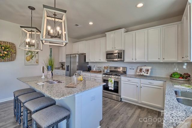 kitchen with white cabinetry, stainless steel appliances, decorative backsplash, visible vents, and wood finished floors