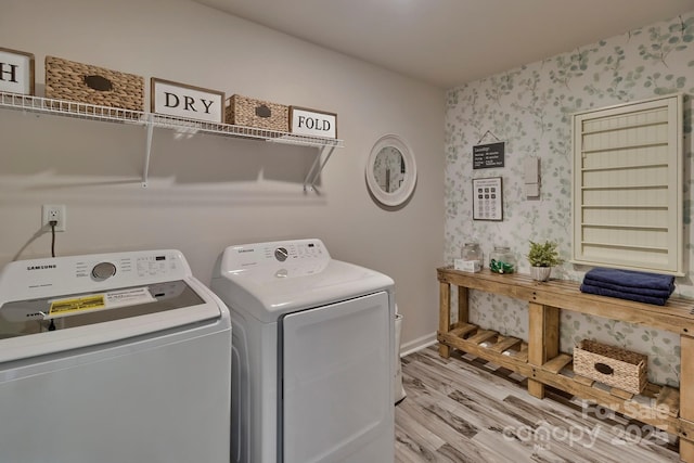 clothes washing area with wood finished floors, laundry area, baseboards, independent washer and dryer, and wallpapered walls