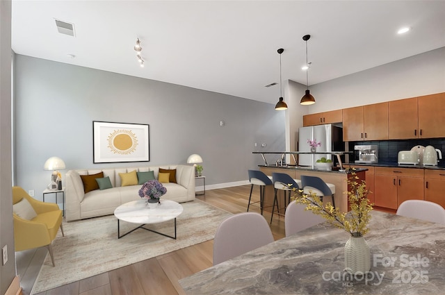 living room featuring light wood finished floors, baseboards, and visible vents