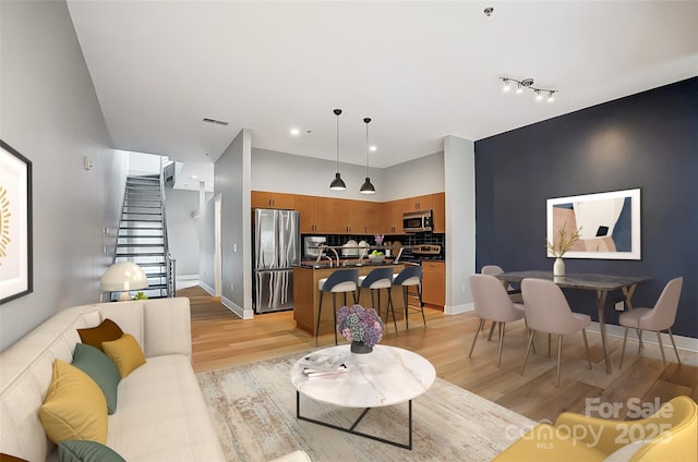 living room featuring light wood-style floors, visible vents, recessed lighting, stairway, and baseboards