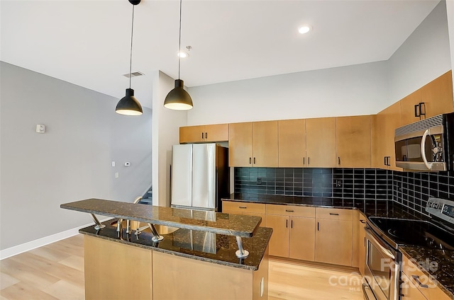 kitchen featuring light wood-style floors, visible vents, a kitchen island, appliances with stainless steel finishes, and decorative backsplash
