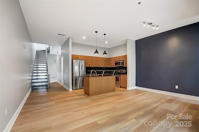 kitchen featuring tasteful backsplash, appliances with stainless steel finishes, light wood finished floors, and dark countertops
