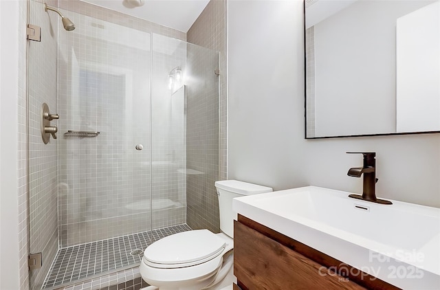 bathroom with toilet, a shower stall, and vanity