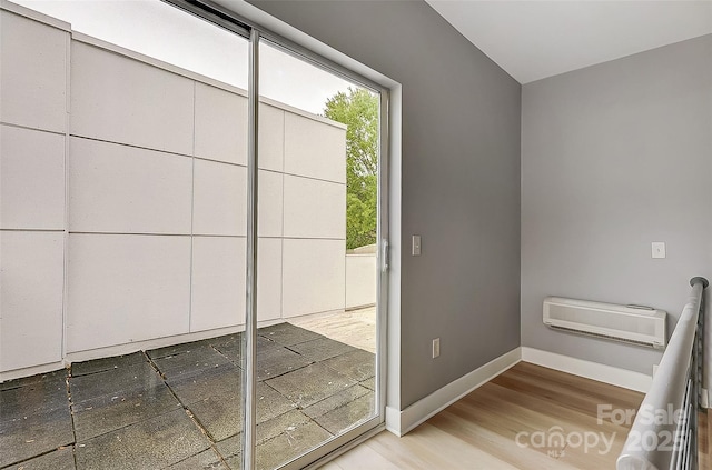 entryway with an AC wall unit, baseboards, and wood finished floors
