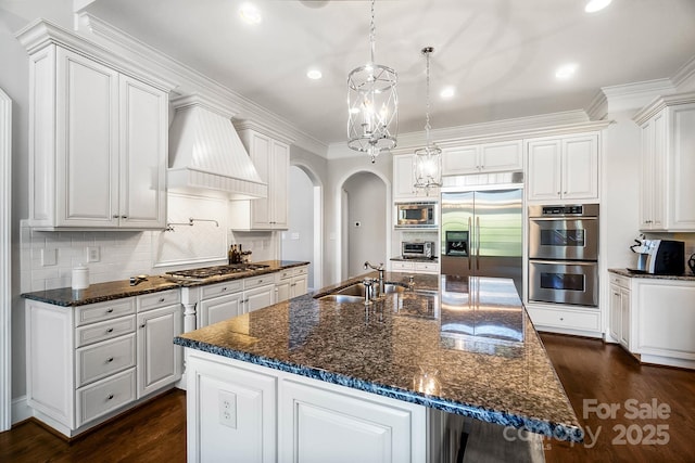 1404 Churchill Downs Dr, Waxhaw, NC 28173 - kitchen featuring white cabinets, a sink, built in appliances, arched walkways, and custom exhaust hood