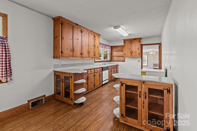 kitchen featuring open shelves, visible vents, wood finished floors, light countertops, and white dishwasher