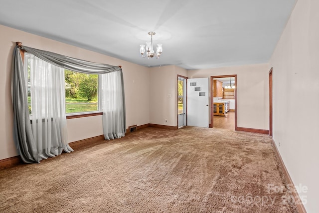 carpeted empty room featuring baseboards and an inviting chandelier