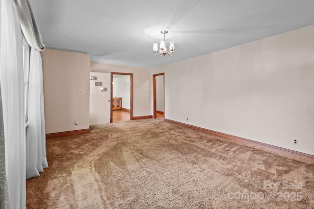 spare room with a chandelier, baseboards, and carpet floors