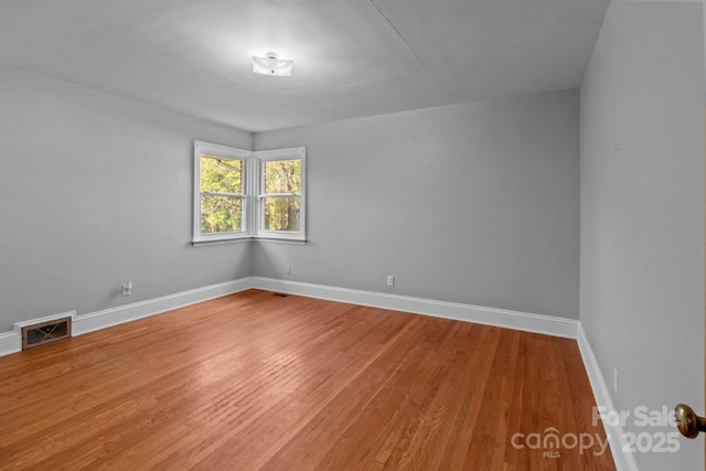 empty room featuring visible vents, baseboards, and wood finished floors