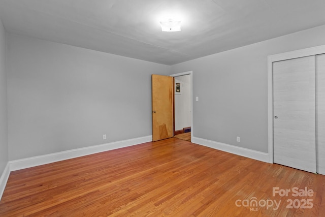 unfurnished bedroom with a closet, light wood-type flooring, and baseboards