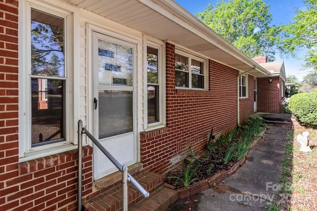 view of exterior entry featuring brick siding