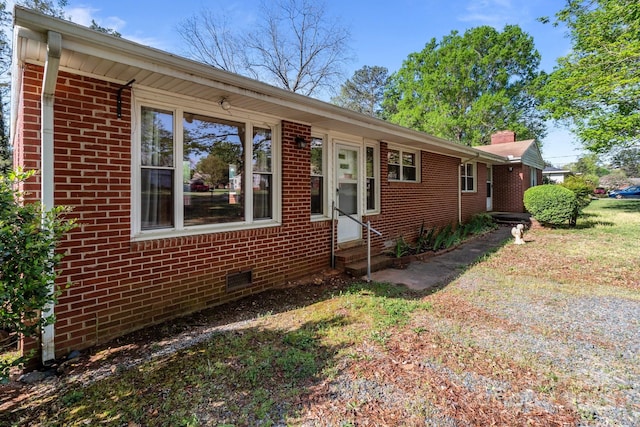 ranch-style house with entry steps, a chimney, and brick siding