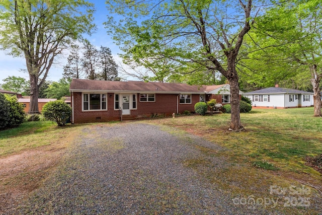ranch-style house featuring brick siding, driveway, a front lawn, and crawl space