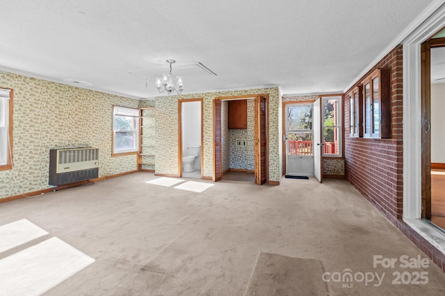 interior space featuring heating unit, a chandelier, a textured ceiling, wallpapered walls, and carpet flooring