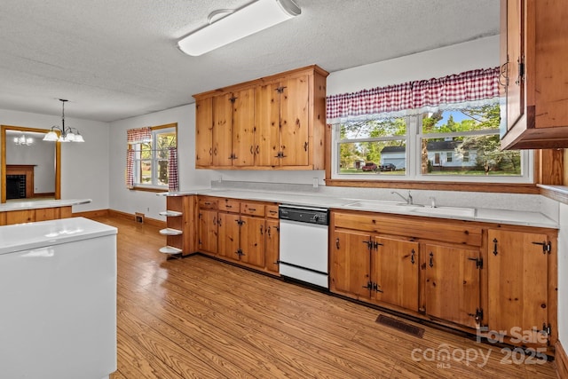 kitchen with light wood-type flooring, visible vents, light countertops, a sink, and white dishwasher