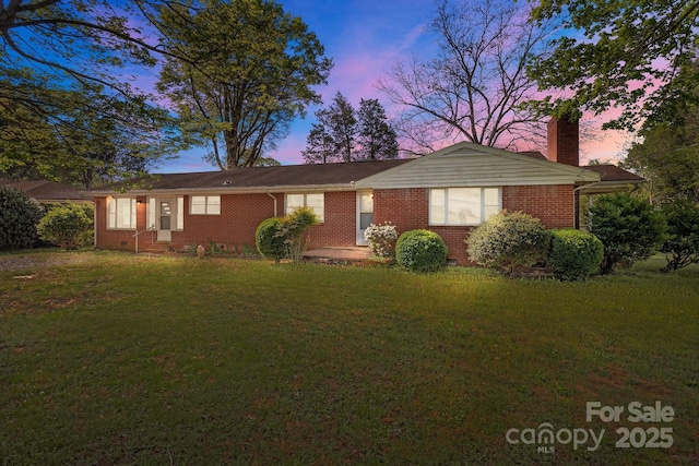 single story home with a yard, brick siding, and a chimney