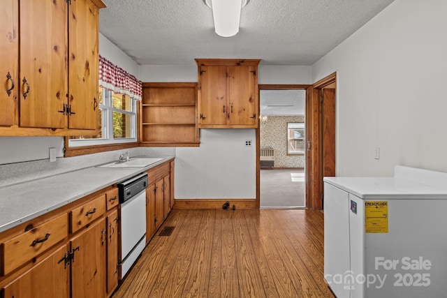 kitchen with light wood-type flooring, light countertops, open shelves, white dishwasher, and a sink