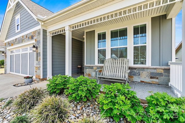 8718 Festival Way, Charlotte, NC 28215 - view of exterior entry featuring a porch, driveway, a garage, and stone siding
