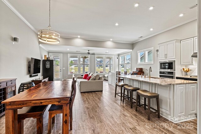 8718 Festival Way, Charlotte, NC 28215 - kitchen with stainless steel appliances, light wood-type flooring, ornamental molding, and a healthy amount of sunlight