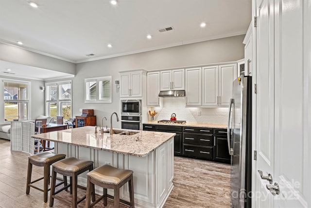 8718 Festival Way, Charlotte, NC 28215 - kitchen with visible vents, a sink, dark cabinetry, a center island with sink, and stainless steel appliances