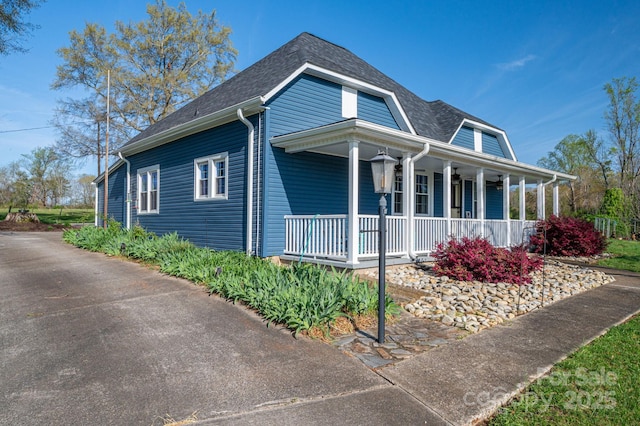 view of side of home featuring roof with shingles and covered porch