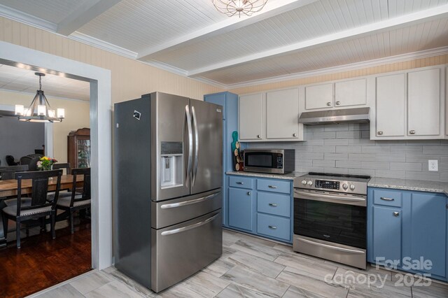 kitchen with appliances with stainless steel finishes, blue cabinets, an inviting chandelier, and under cabinet range hood
