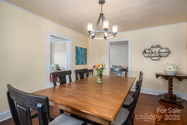 dining room featuring ornamental molding, baseboards, a notable chandelier, and dark wood finished floors