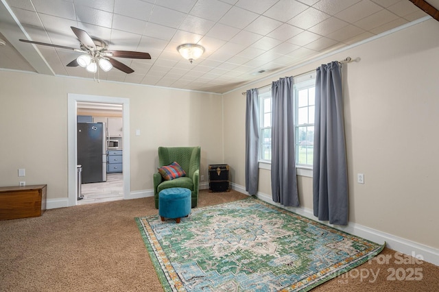 sitting room featuring ornamental molding, a ceiling fan, visible vents, carpet flooring, and baseboards