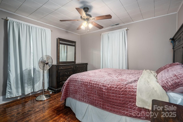 bedroom featuring visible vents, ornamental molding, ceiling fan, and wood finished floors