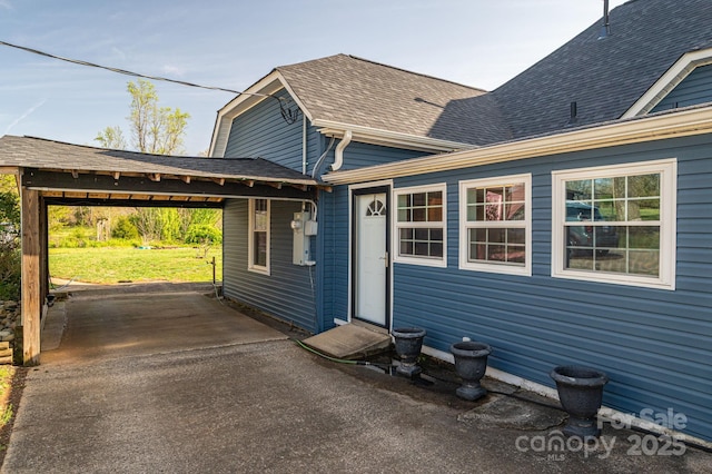 exterior space with aphalt driveway, roof with shingles, and a yard