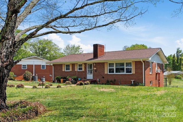 ranch-style house with a chimney, brick siding, a front yard, and cooling unit