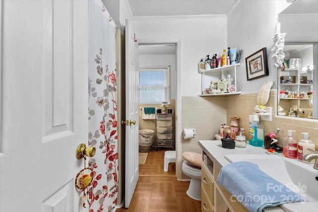 full bath with toilet, ornamental molding, tile walls, vanity, and a wainscoted wall