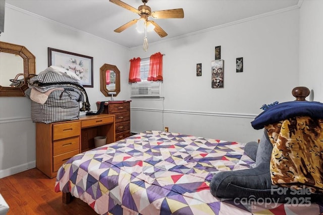 bedroom featuring wood finished floors, crown molding, a ceiling fan, and baseboards