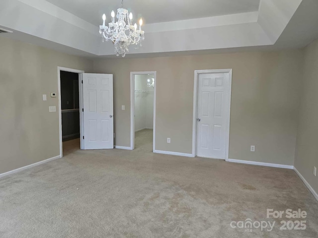 5713 Falkirk Ln, Matthews, NC 28104 - unfurnished bedroom with a tray ceiling, a chandelier, carpet floors, and a walk in closet